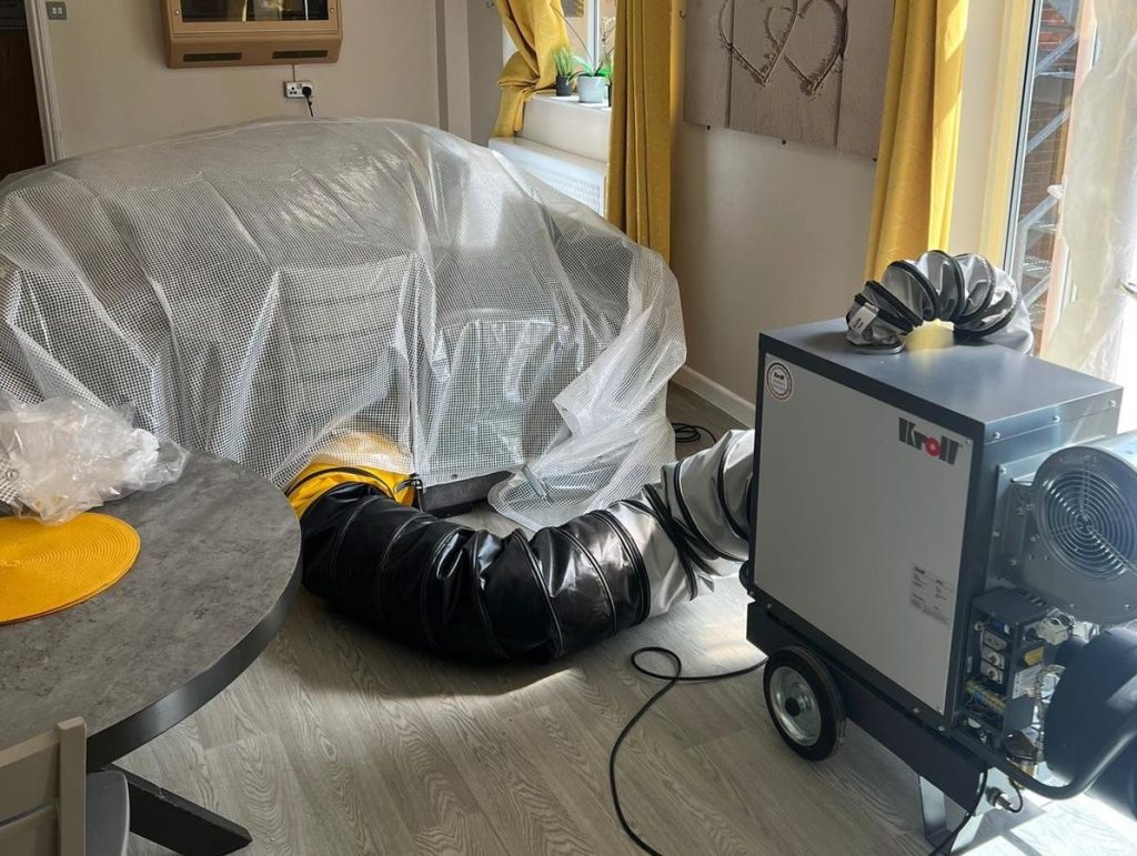 A heat treatment for pest control in progress, with a sofa wrapped in plastic and the heat treatment equipment in the foreground